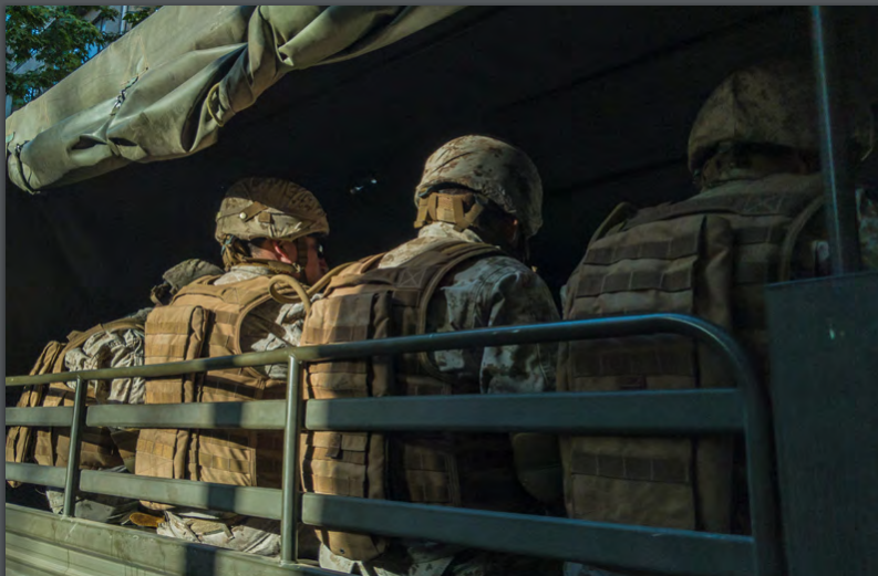 A group of soldiers sitting in the back of a military truck