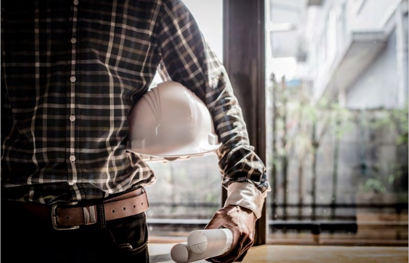 Man in hard hat and plaid shirt holding document