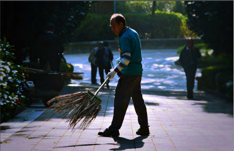 Man sweeping sidewalk with broom