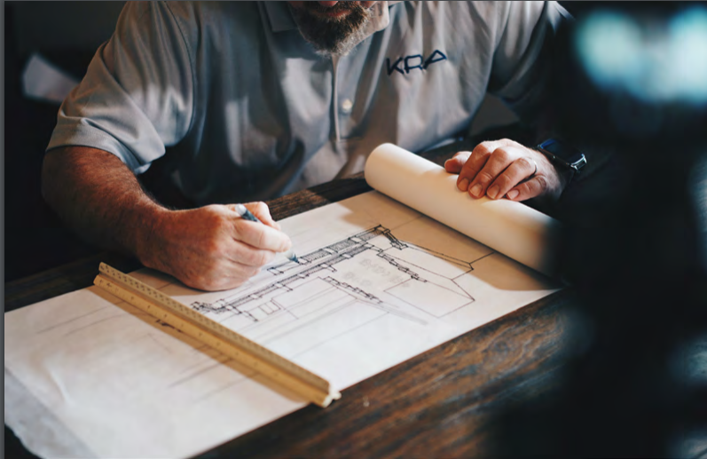 Engineer drawing on blueprint at table