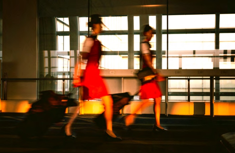 Two women in red dresses strolling at airport